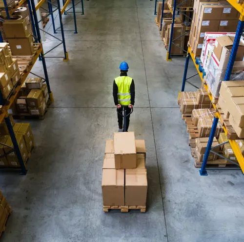 Mann som jobber på lager, trekker kartongesker og sikrer effektiv logistikk og arbeidsflyt